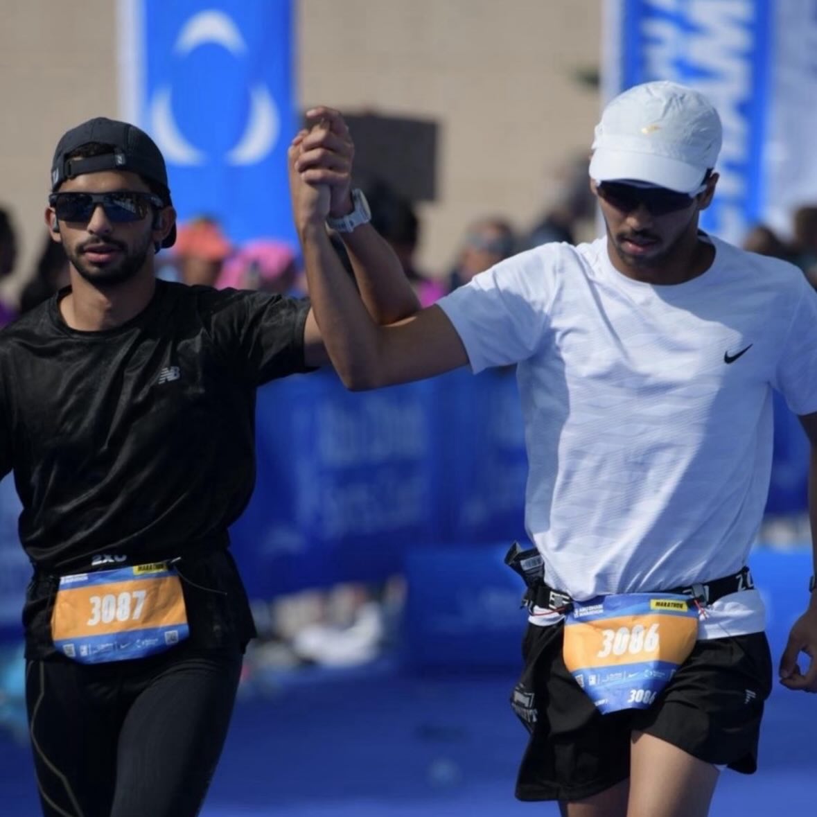 Two runners crossing a race finish in sports sunglasses